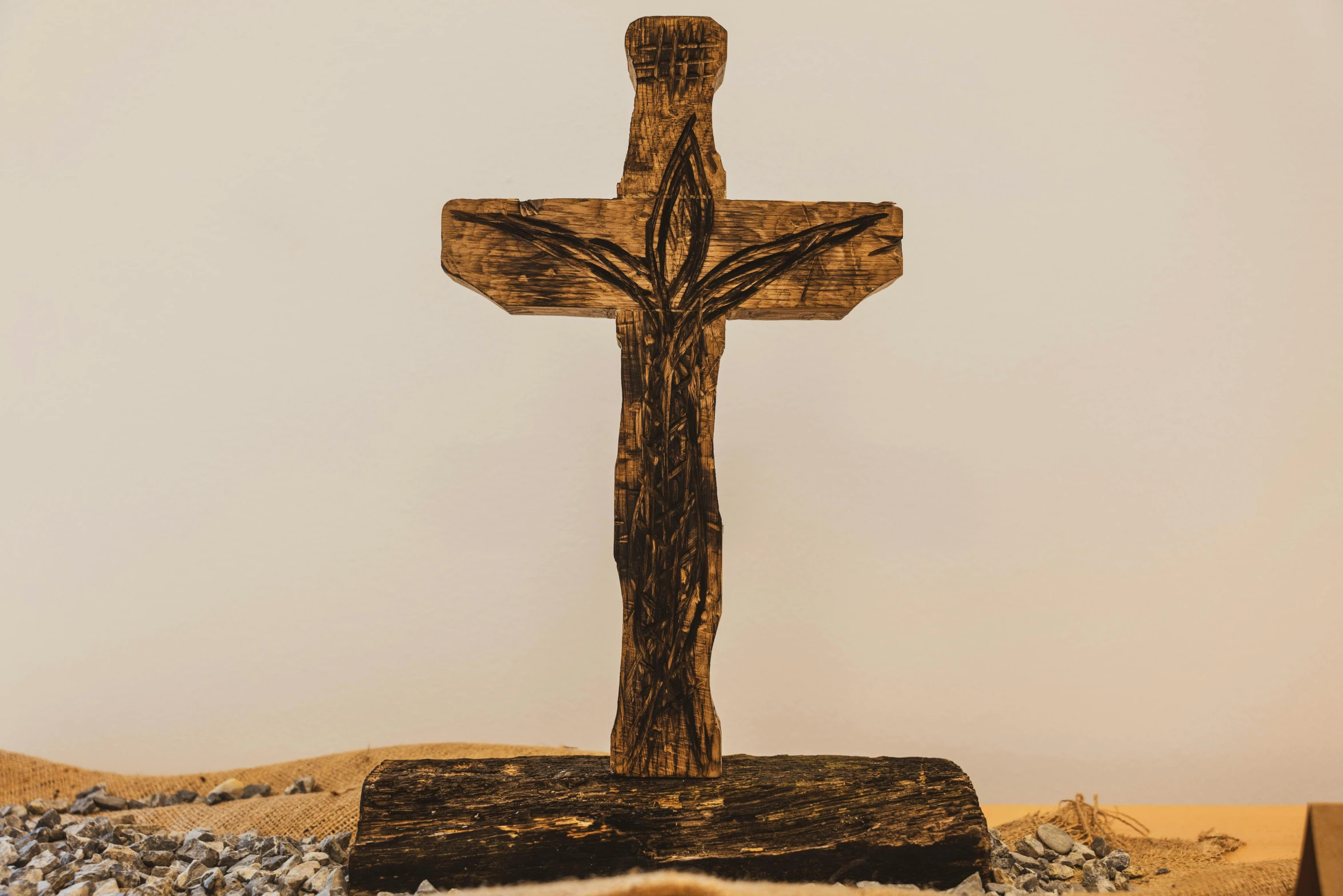 a wooden cross on a table with a rug underneath it