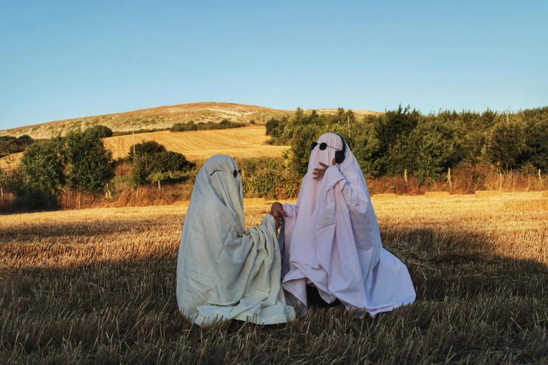 two ghostly women wearing white clothing in a field