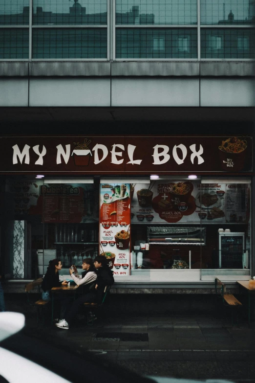 some people sitting outside a restaurant in the street