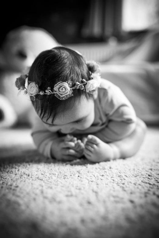 baby girl sitting on rug, looking down at floor