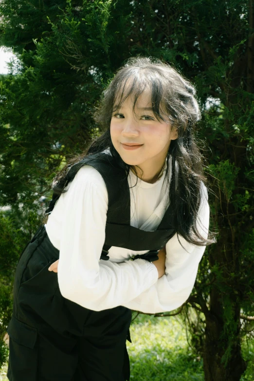 a young person standing in front of some trees