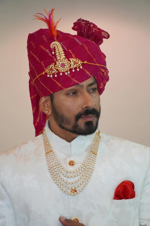a man wearing a turban with pearls and a red jacket