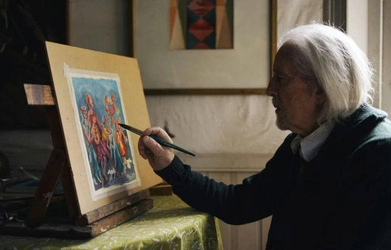 a man holding a painting brush near an easel