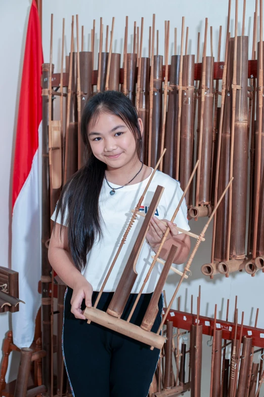 an asian girl in front of lots of pipes and wooden rods