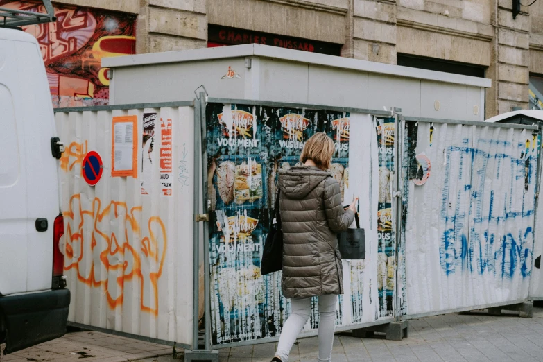 the woman in a winter coat is standing in front of a covered storage box