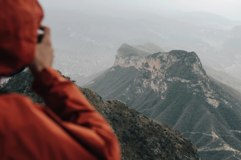 a woman with red coat on the top of a mountain with trees