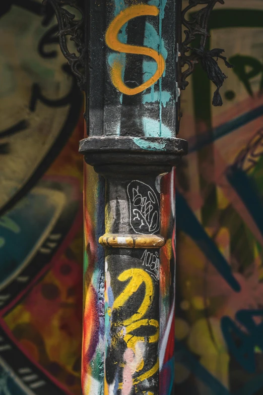 graffiti all over a pole near a wall