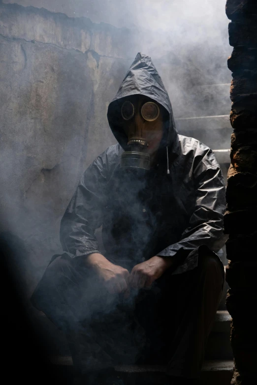 a man sitting in the mist with a hood and goggles