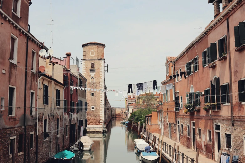 three boats parked in the water beside buildings on a narrow waterway