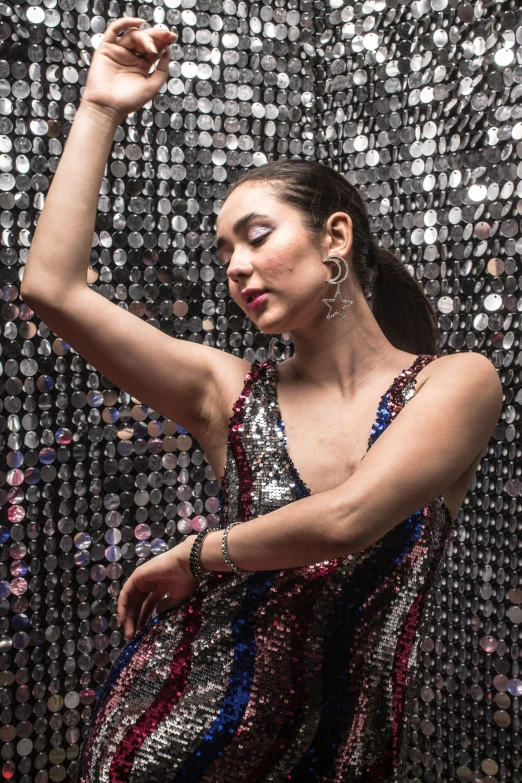 a woman in glitter dress next to silver wall