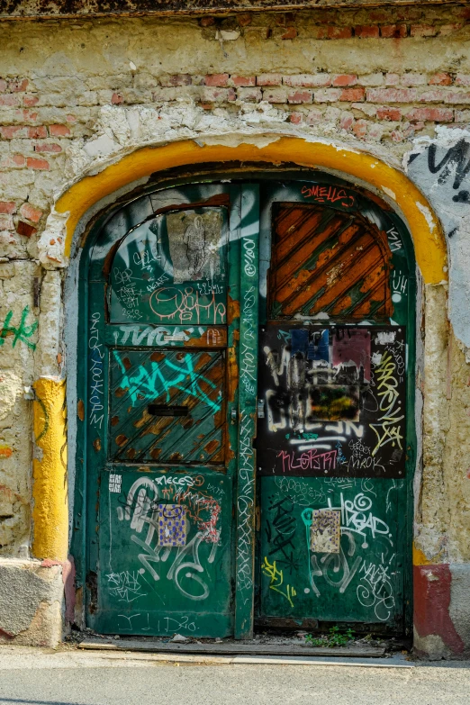 a green door with graffiti is on the side of a building