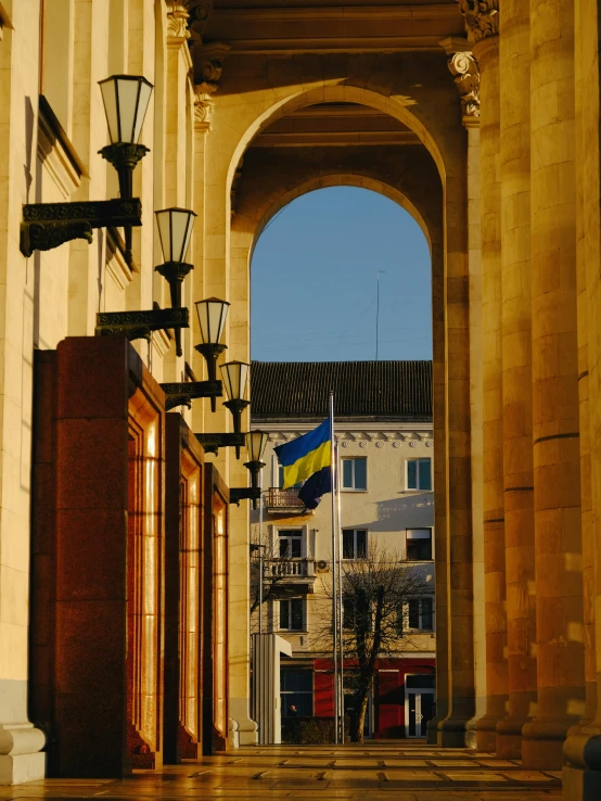 a big archway near a building has a flag on it