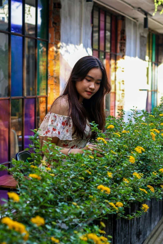 a woman sitting on a bench looking down at a yellow flower