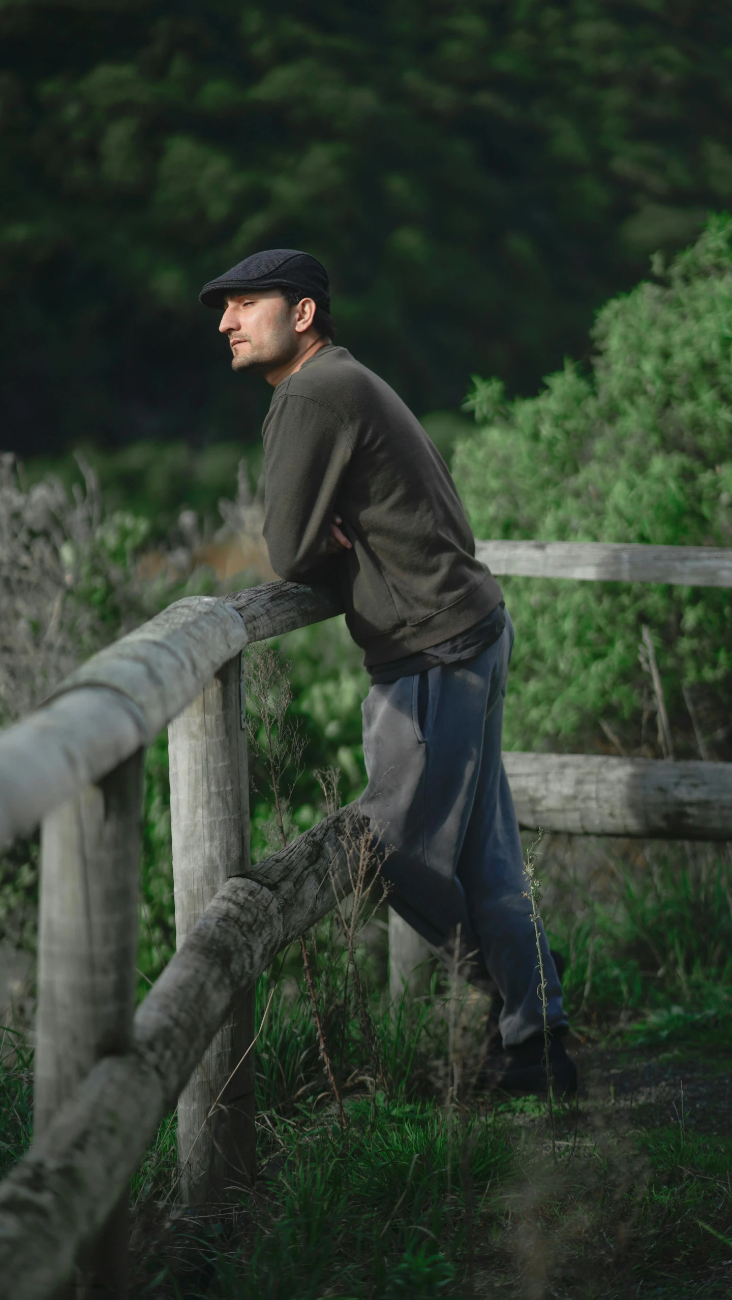 a young man leaning on a wooden fence