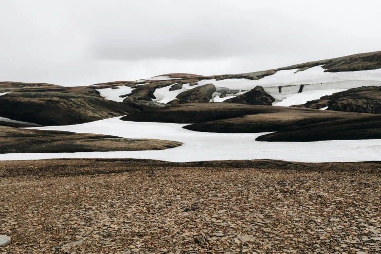 a single lone rock stands among the snow capped mountains