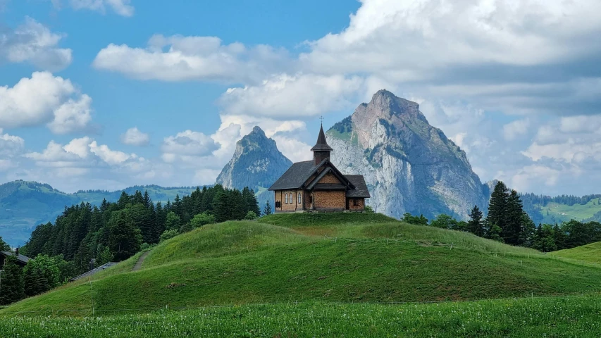 a small church on the side of a green hill