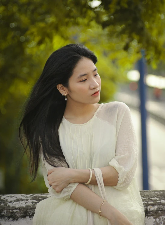 a woman sitting on a wall in front of trees