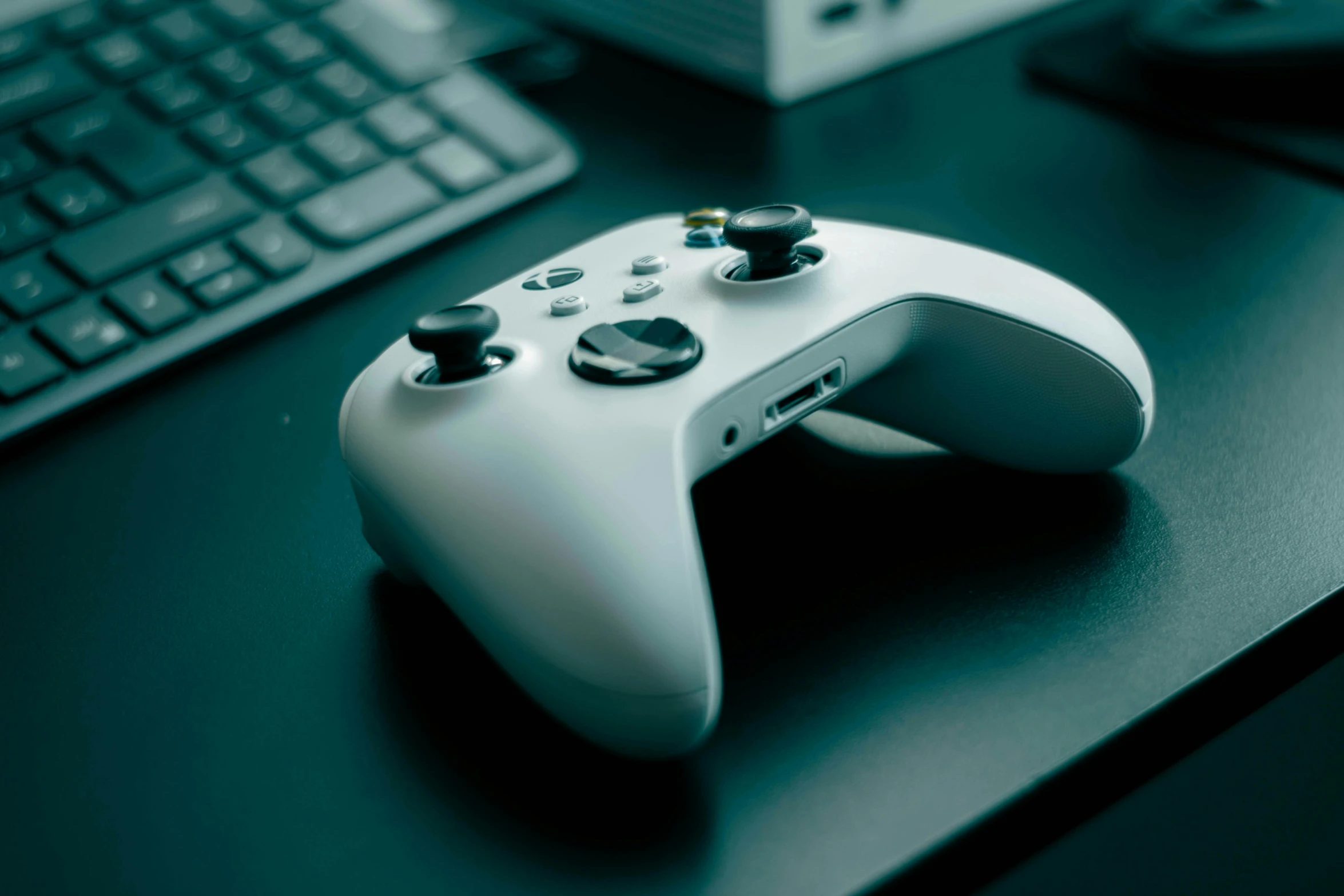 a white game controller next to a keyboard