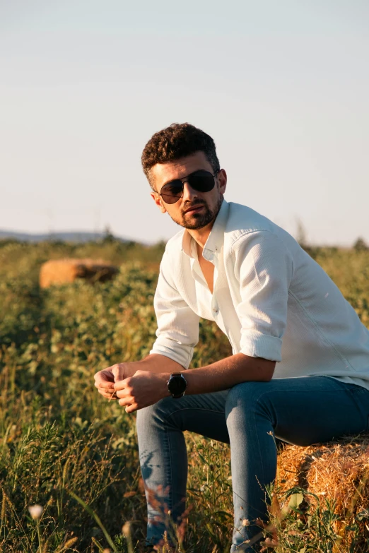 the man is kneeling in the field and posing for the camera