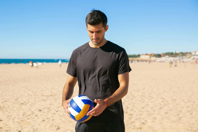 a man holding a colorful ball on the beach