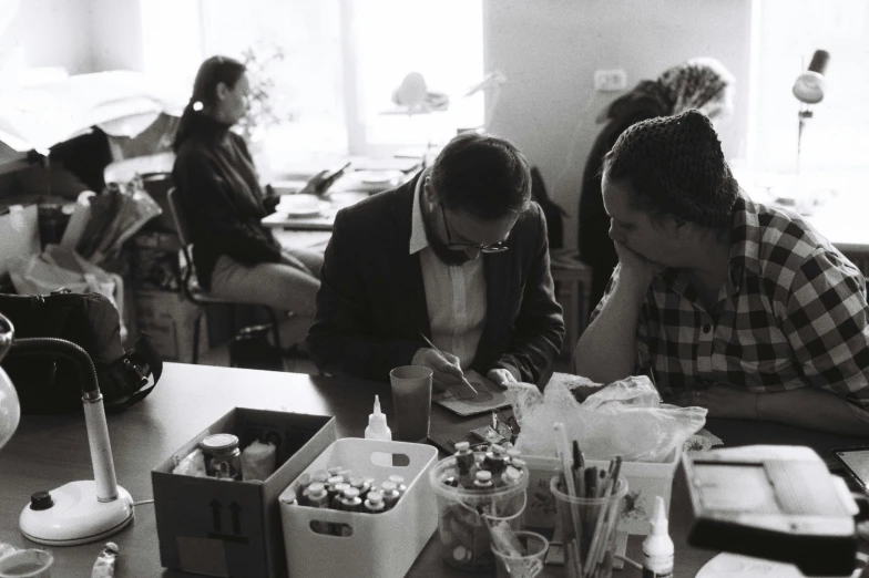 two people sitting at a table with several pastries on it