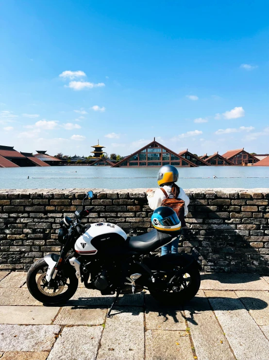 a person is sitting on a motorcycle next to some water