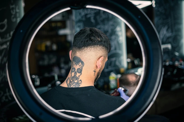 a man looking into a mirror with a tattoo on his neck