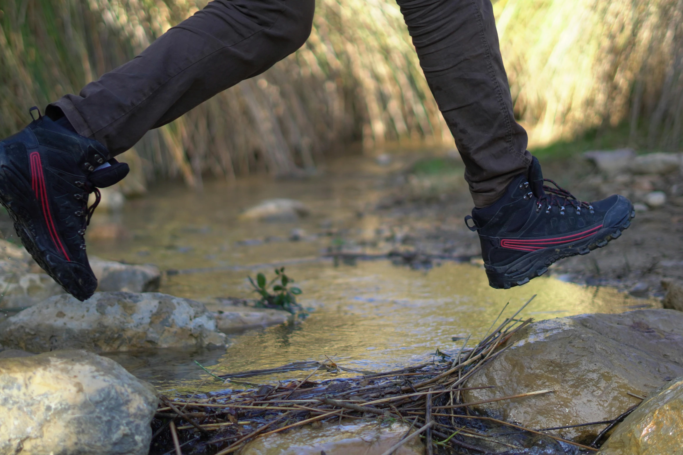 two feet in shoes jump over a small stream