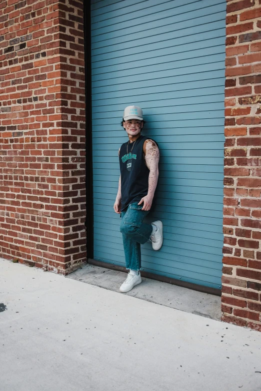 a young man leaning on a wall next to a garage door