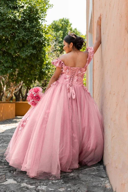 woman in a pink gown leaning against a wall