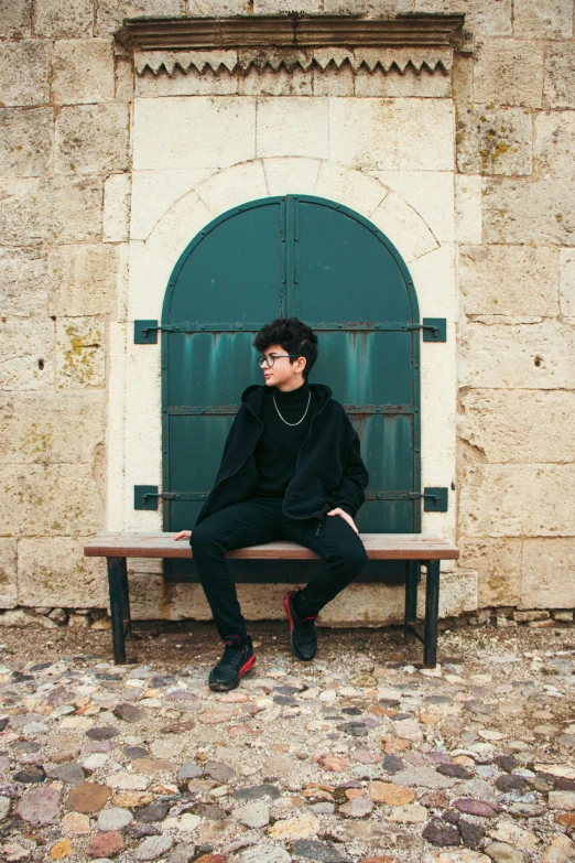 a boy in black jacket sitting on bench near window