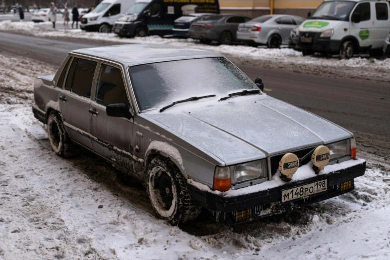 a parked car is covered in snow on the side of a street