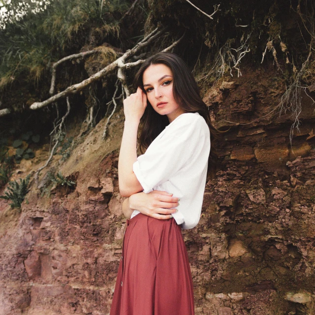 woman leaning against a tree with her arms crossed