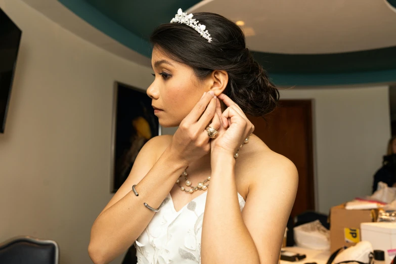 a beautiful woman wearing a tiara putting on her wedding dress