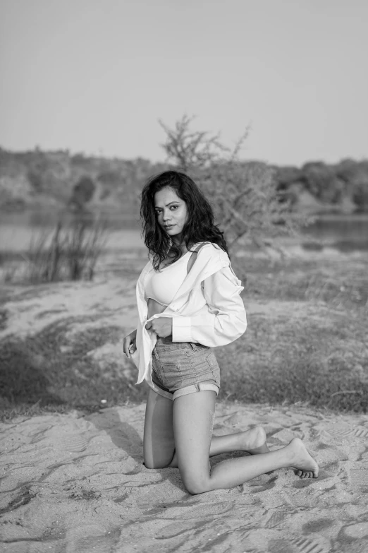 a woman wearing underwear sitting in the sand