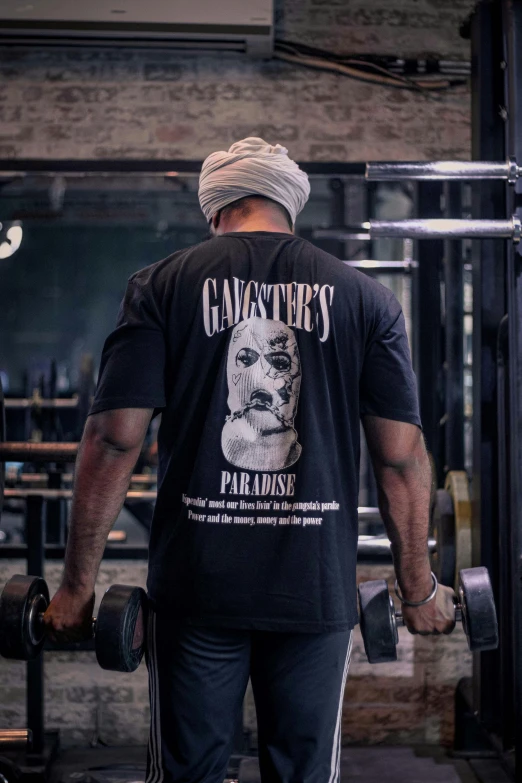 a man wearing a gym t - shirt is lifting a dumbbell