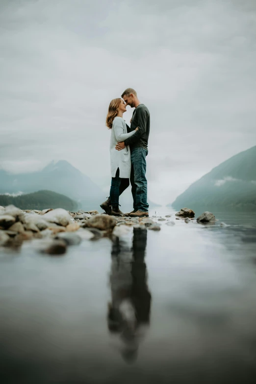 a beautiful couple is emcing on a rocky beach