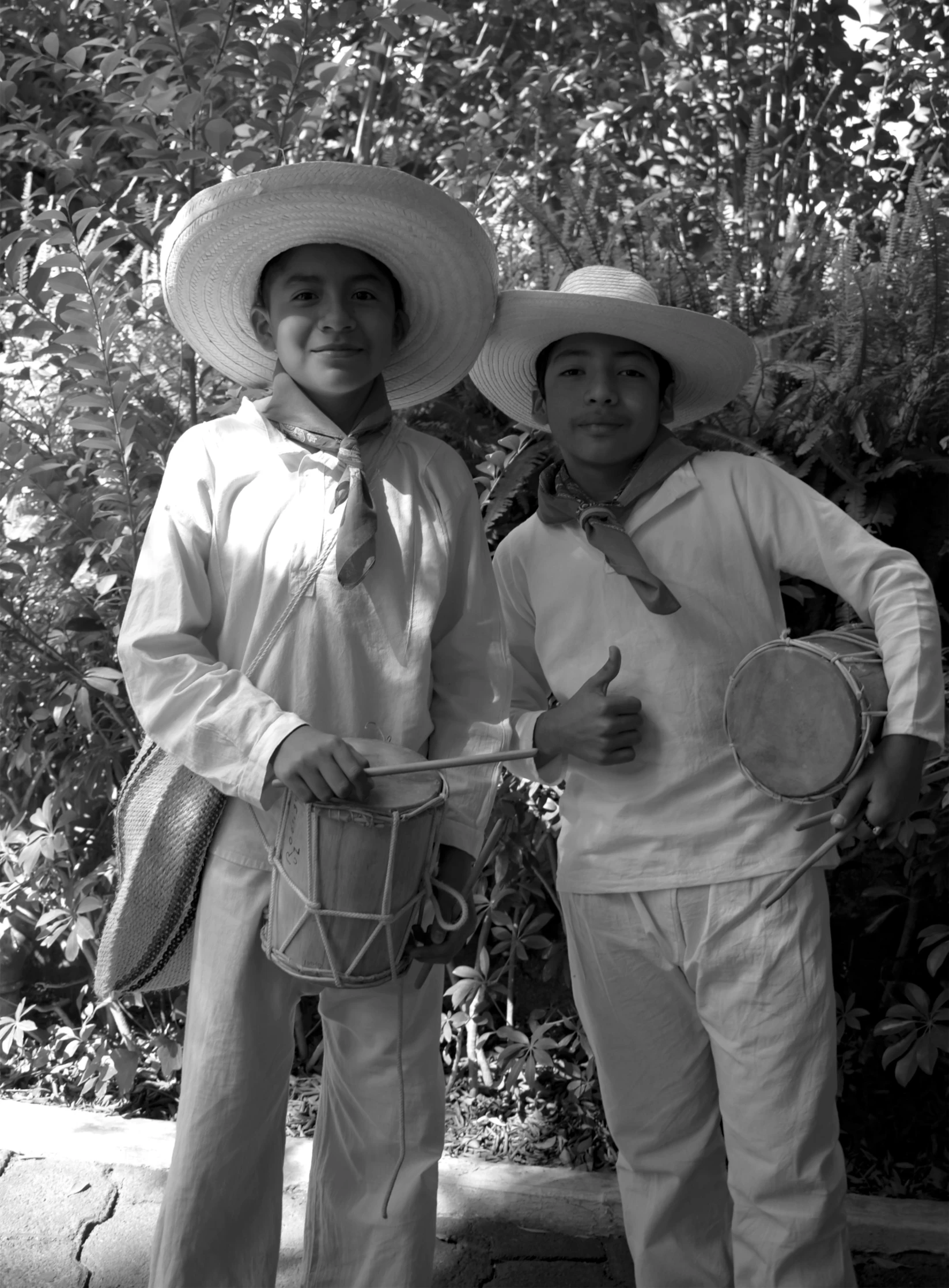 two people standing holding hats near trees