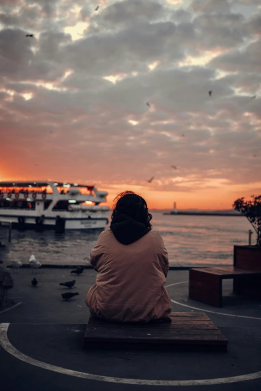 woman sitting on a bench in front of some boats