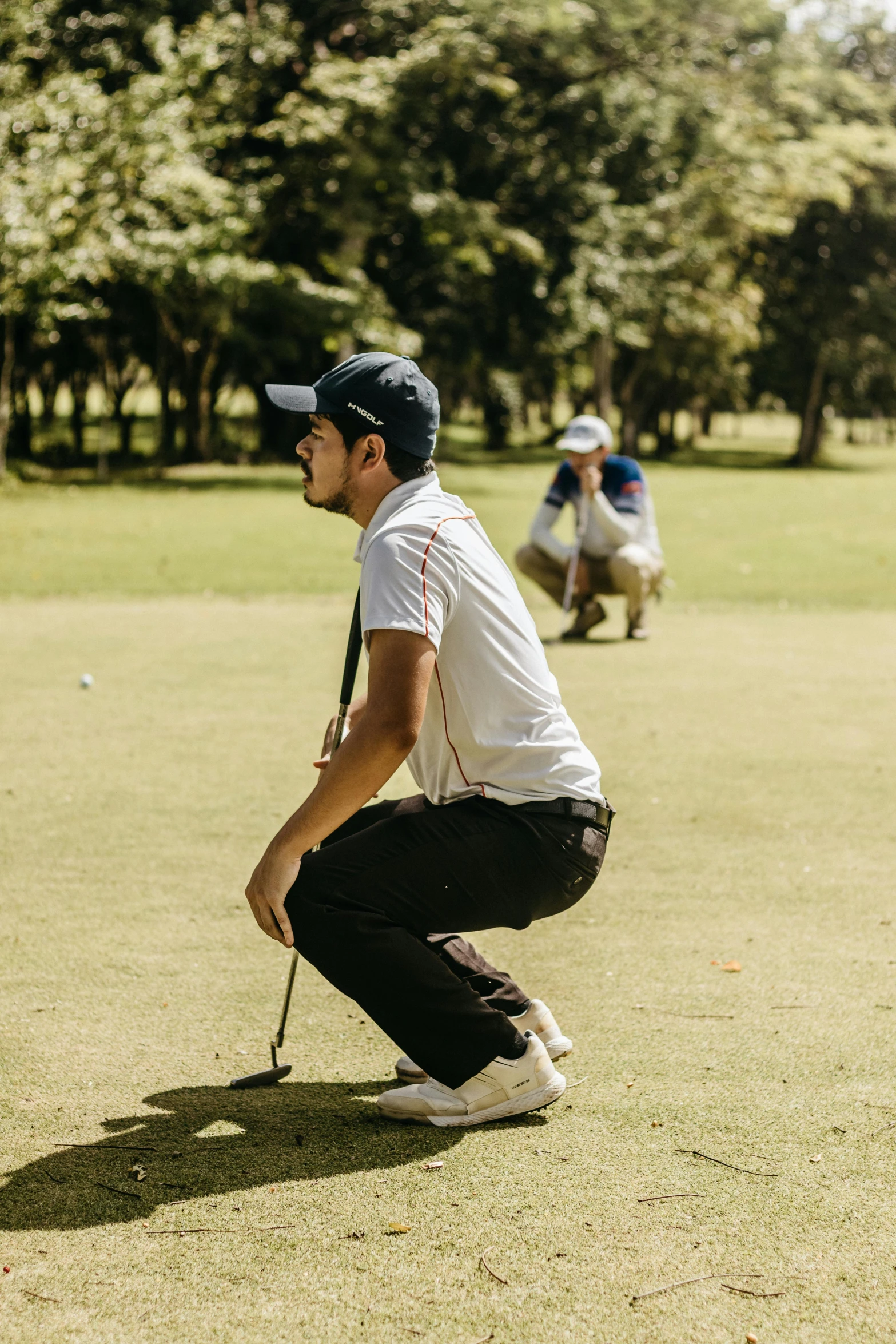 a man kneeling down holding a golf club and a ball in his hand