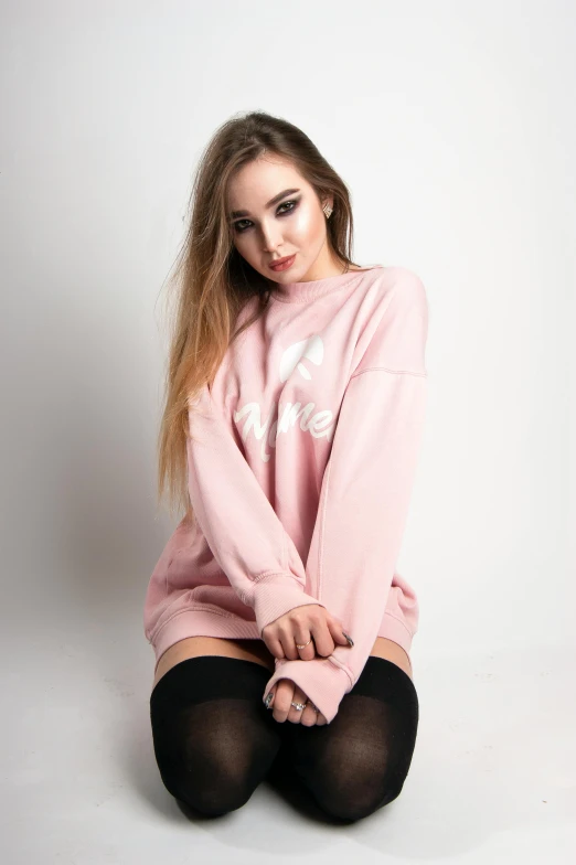 a girl in a pink sweater is sitting down
