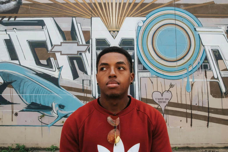 a man standing in front of a mural wearing a red and white shirt