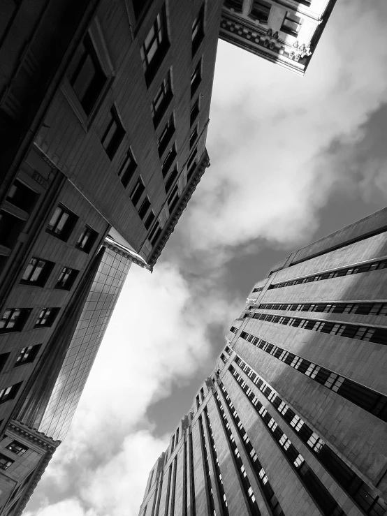 an upward view of some buildings with a cloudy sky in the background