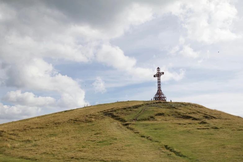 a cross atop a hill made from wood and grass