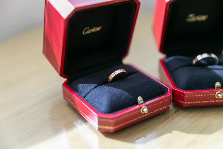 two red cases with rings inside them sitting on top of a table