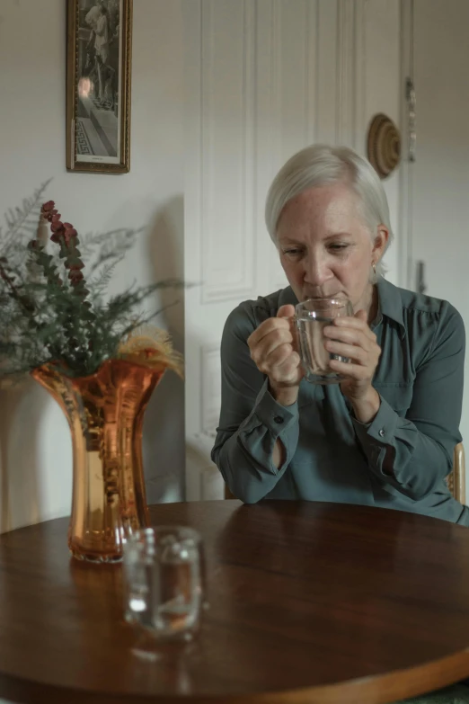 a woman drinking from a glass at a dining table