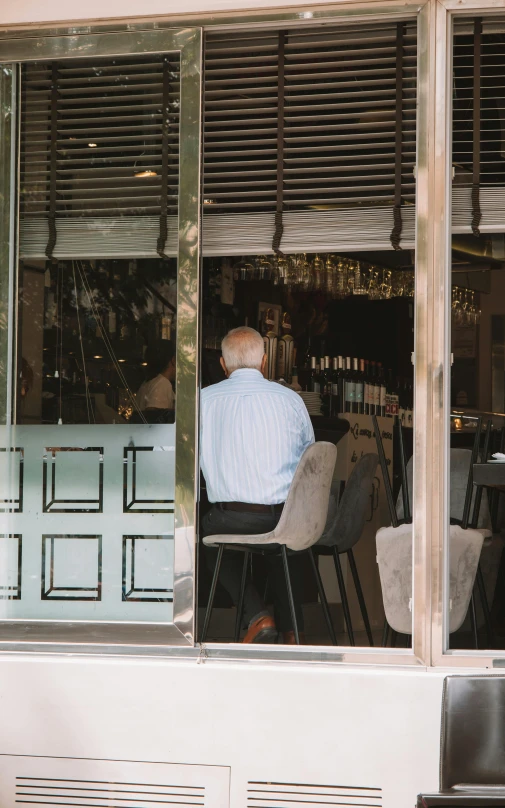 an older man sitting in a chair at a bar