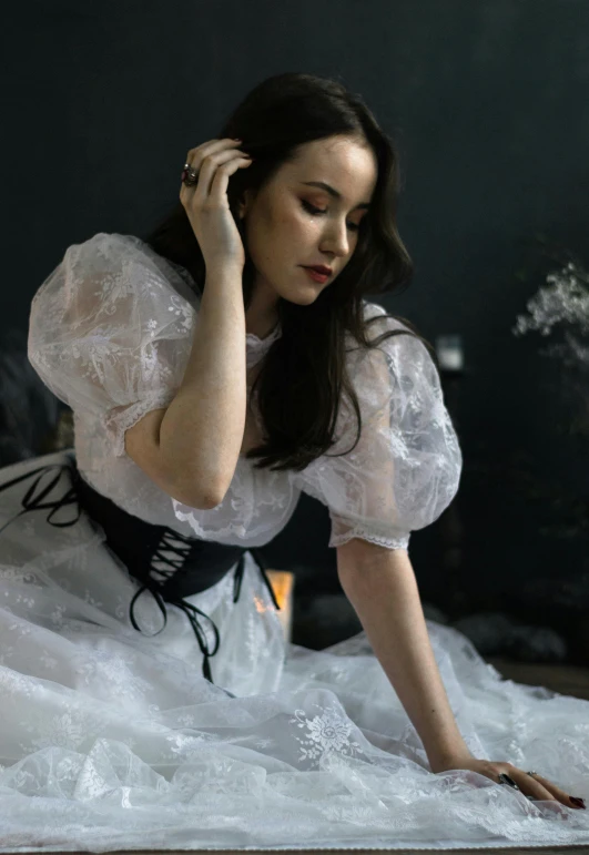 a woman in white clothing kneeling down on a chair