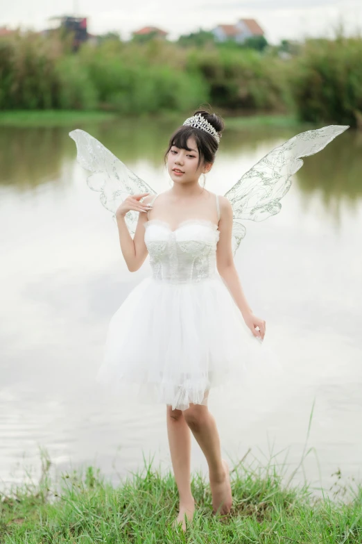 a woman wearing a fairy costume standing next to a lake