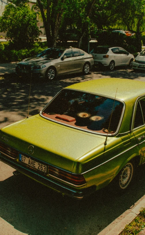 an old green car parked in the driveway